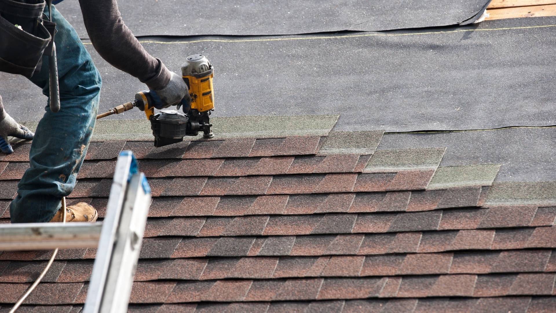 professional standing on roof of home and using tool