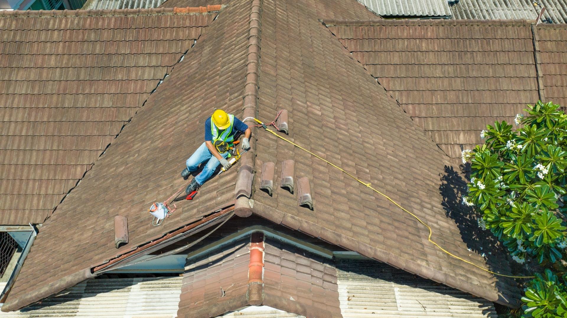professional in yellow work hat working on roof of home