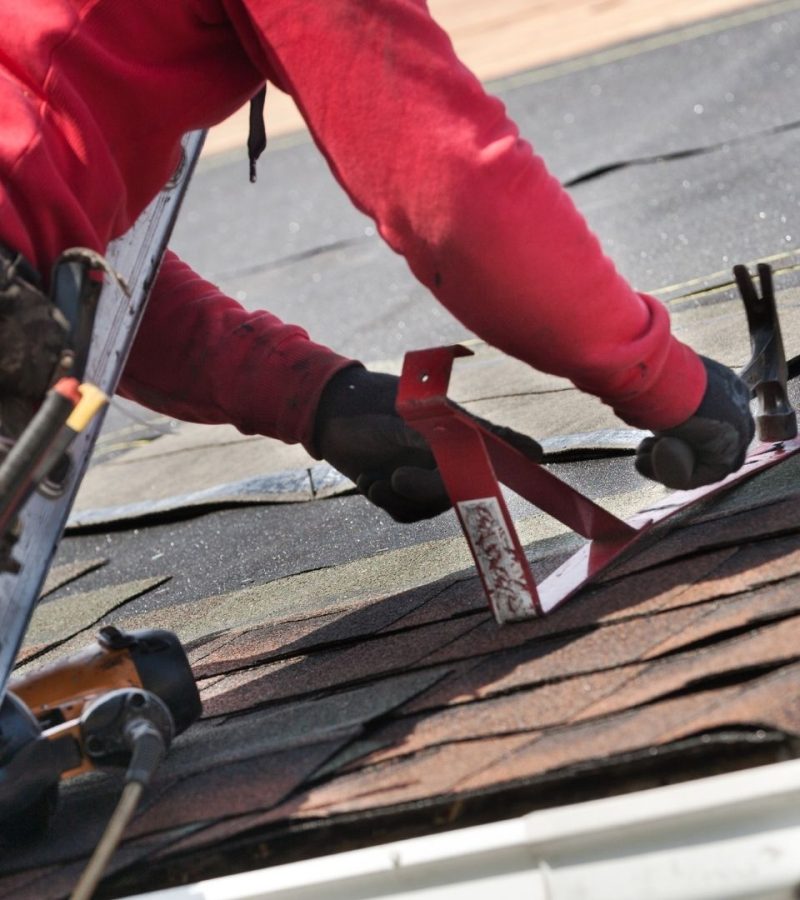 professional working on roof home while on ladder