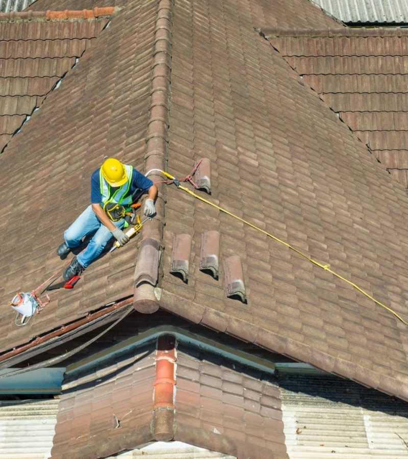 professional in yellow work hat working on roof of home